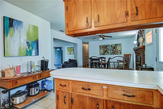 kitchen with light countertops, brown cabinets, a ceiling fan, and light tile patterned floors