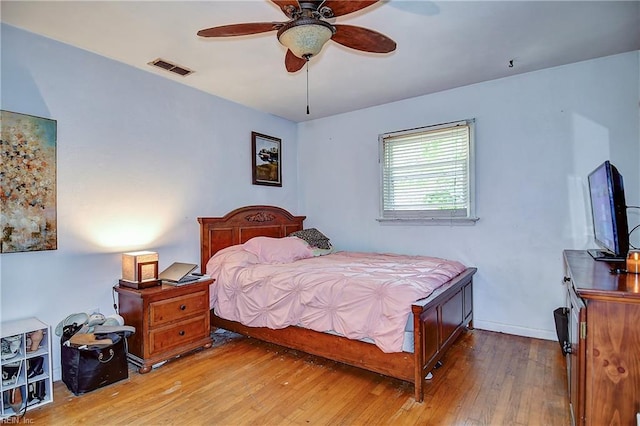 bedroom featuring visible vents, baseboards, ceiling fan, and hardwood / wood-style flooring