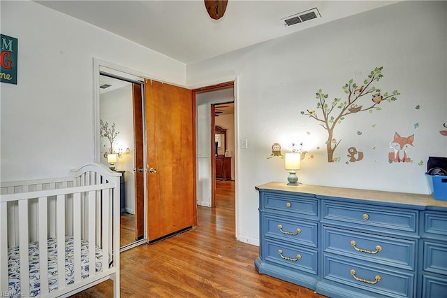 bedroom featuring a closet, wood finished floors, and visible vents