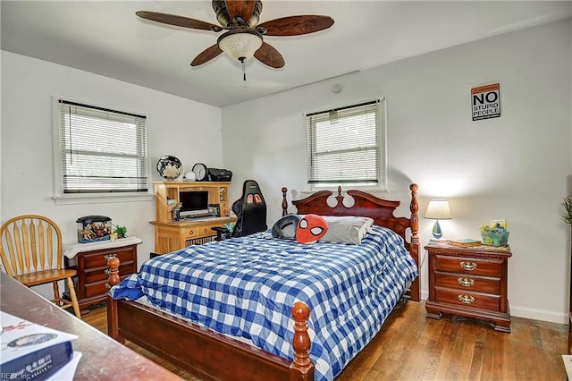 bedroom with baseboards, a ceiling fan, hardwood / wood-style floors, and multiple windows