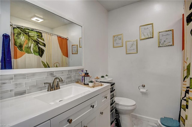 bathroom featuring vanity, marble finish floor, toilet, baseboards, and tasteful backsplash