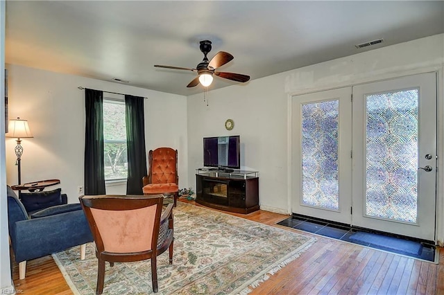 living room with visible vents, a ceiling fan, and wood-type flooring