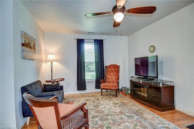 sitting room featuring a ceiling fan, baseboards, visible vents, and wood finished floors