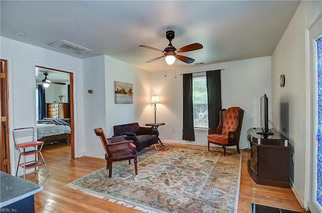 living area featuring visible vents, a ceiling fan, and light wood finished floors