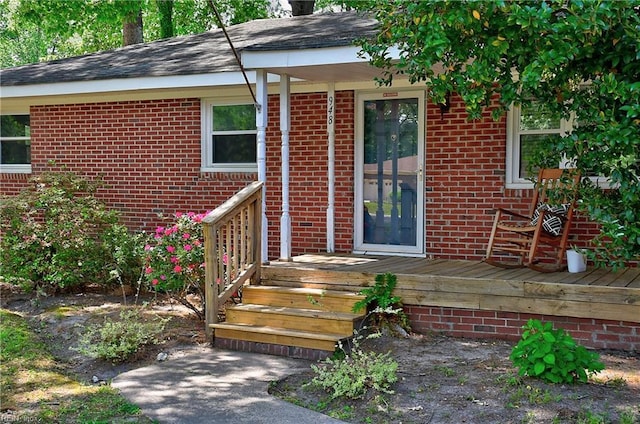 property entrance featuring brick siding and a wooden deck