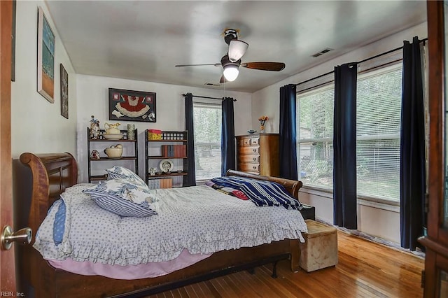 bedroom featuring ceiling fan, wood finished floors, and visible vents