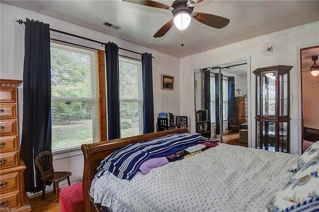bedroom with a ceiling fan, baseboards, visible vents, and wood finished floors