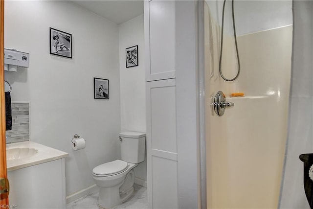bathroom with vanity, toilet, marble finish floor, baseboards, and a shower