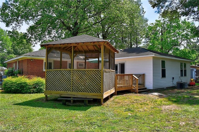 back of property with a lawn, crawl space, a wooden deck, and a shingled roof