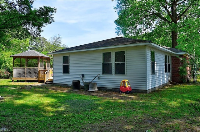 back of property featuring a lawn, crawl space, and a gazebo