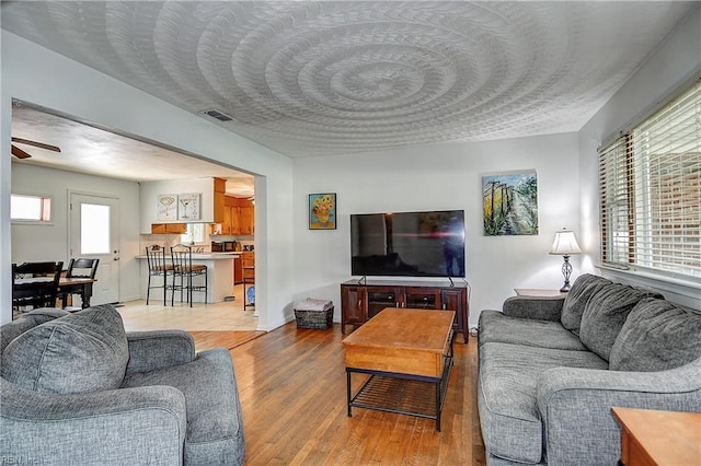 living area with visible vents, a ceiling fan, and light wood finished floors