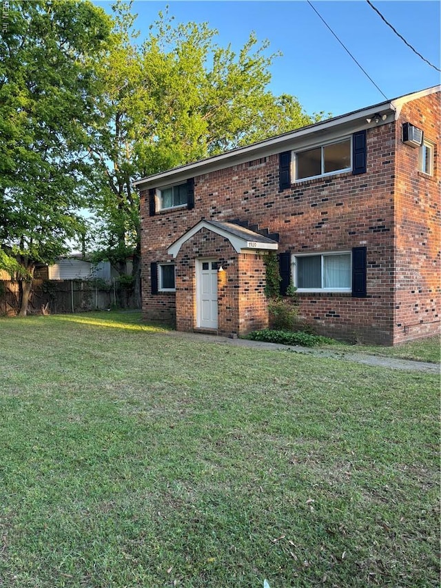 traditional home featuring brick siding, fence, and a front yard