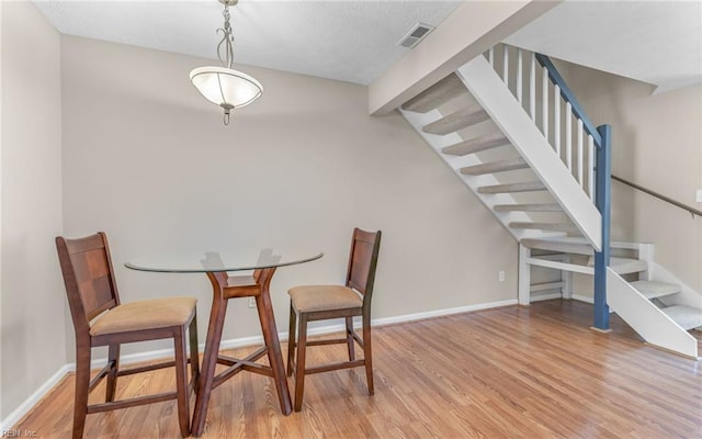 dining space with visible vents, light wood-style flooring, baseboards, and stairway