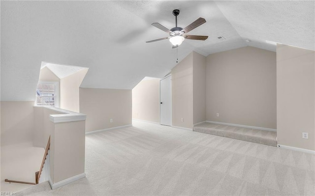 bonus room featuring lofted ceiling, baseboards, ceiling fan, a textured ceiling, and carpet flooring