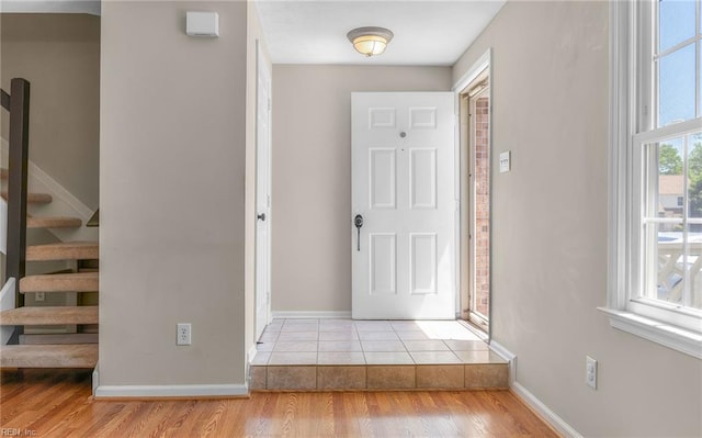entryway with baseboards, stairs, and wood finished floors