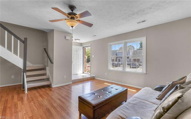 living area featuring visible vents, baseboards, stairs, and wood finished floors