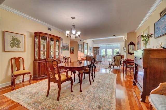 dining room with a chandelier, ornamental molding, light wood-style floors, and baseboards