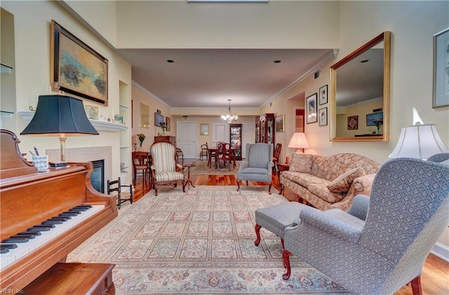 living area with wood finished floors, a glass covered fireplace, crown molding, and a chandelier