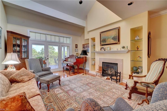 living area with wood finished floors, built in features, a glass covered fireplace, and french doors