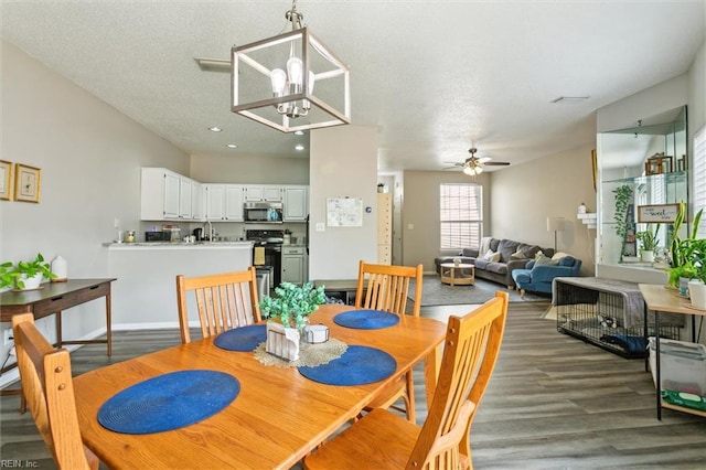 dining space with a textured ceiling, ceiling fan with notable chandelier, recessed lighting, baseboards, and wood finished floors