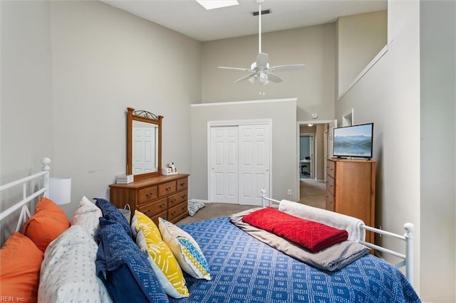 carpeted bedroom featuring ceiling fan, high vaulted ceiling, a skylight, visible vents, and a closet