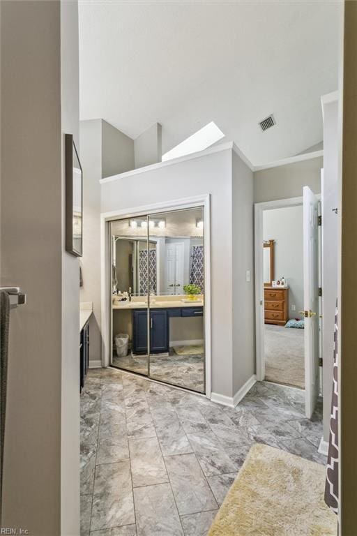 bathroom with a skylight, visible vents, marble finish floor, and vanity