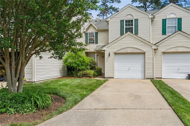multi unit property with an attached garage, concrete driveway, and a front lawn