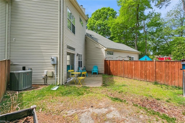 rear view of property featuring a lawn, a patio, central AC, and fence