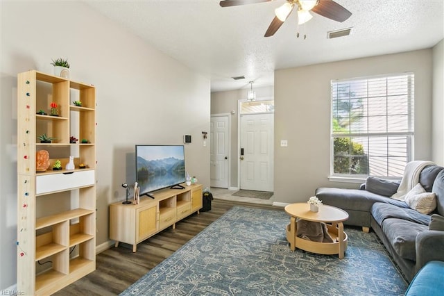 living area featuring dark wood-style flooring, ceiling fan, a textured ceiling, baseboards, and visible vents