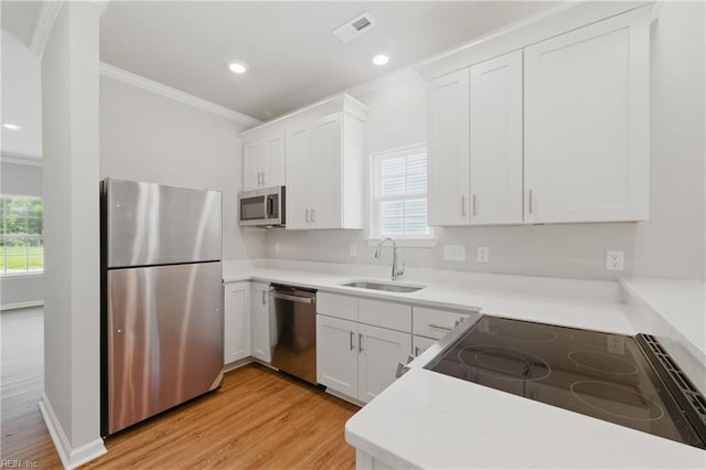 kitchen featuring crown molding, a sink, light wood-style flooring, and appliances with stainless steel finishes