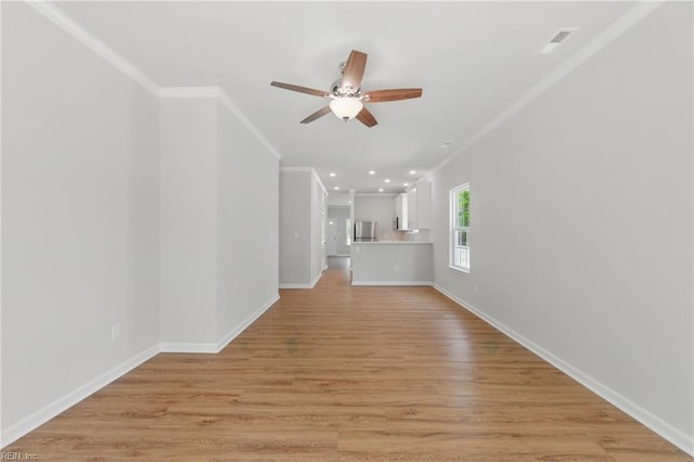 unfurnished living room featuring crown molding, baseboards, ceiling fan, and visible vents