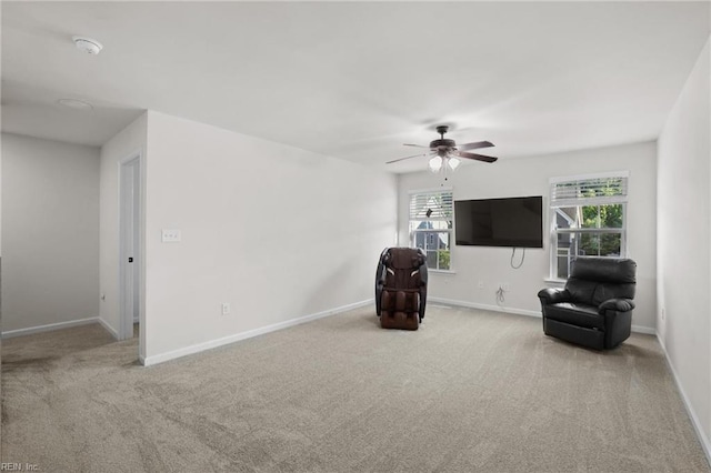 sitting room with baseboards, ceiling fan, and carpet