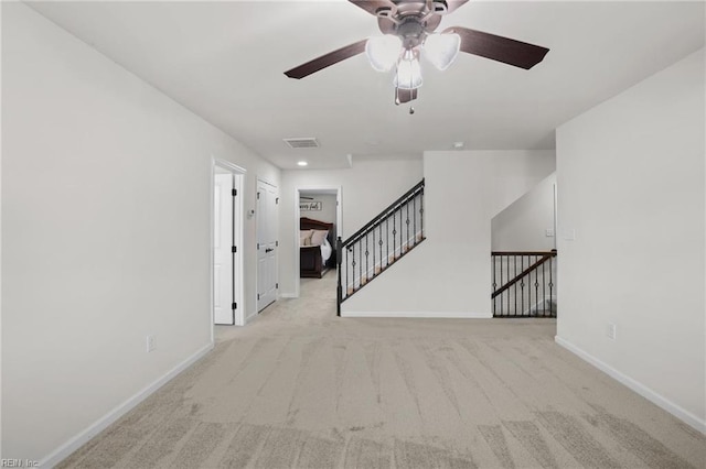 carpeted spare room featuring a ceiling fan, baseboards, and visible vents