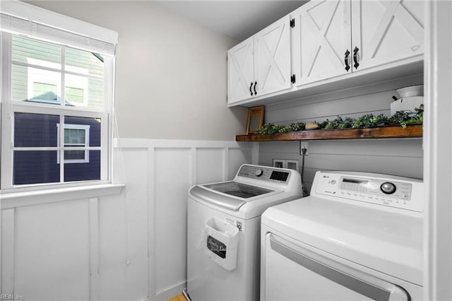 laundry area featuring cabinet space, a decorative wall, a wainscoted wall, and washer and dryer