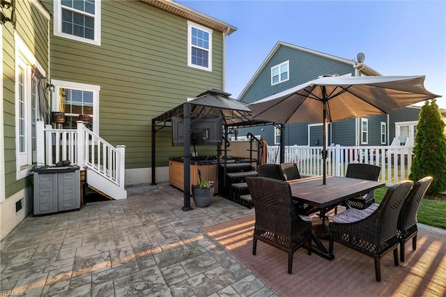 view of patio / terrace featuring a gazebo, a hot tub, fence, and outdoor dining space