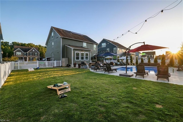 back of property with a residential view, a fenced in pool, a fenced backyard, a yard, and a patio