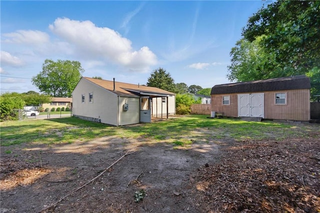 back of property featuring fence, an outbuilding, and a storage unit