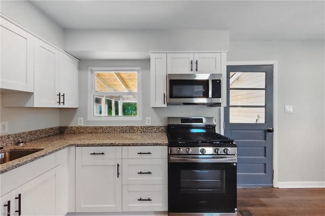 kitchen featuring white cabinets, stainless steel appliances, light stone counters, and dark wood-type flooring