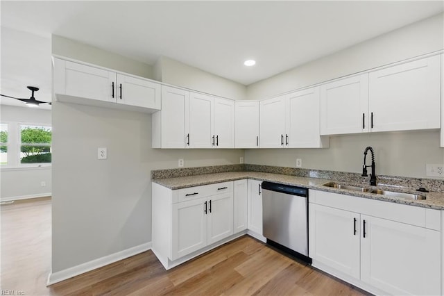 kitchen featuring baseboards, light stone counters, a sink, light wood finished floors, and dishwasher