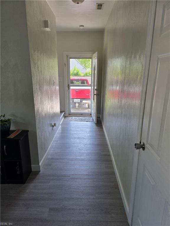 corridor featuring baseboards, visible vents, and wood finished floors