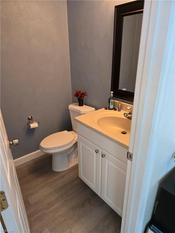 bathroom with toilet, wood finished floors, and vanity