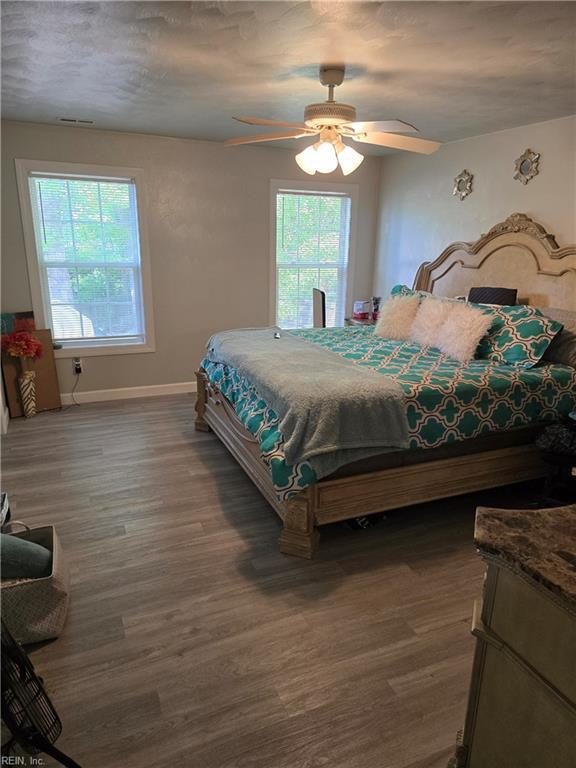 bedroom with baseboards, a ceiling fan, multiple windows, and wood finished floors