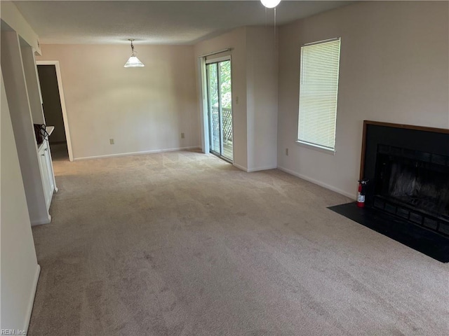 unfurnished living room with baseboards, a fireplace with flush hearth, and light carpet
