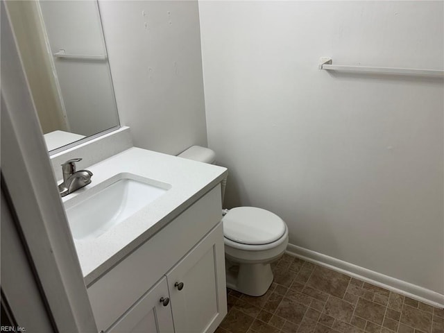 bathroom featuring vanity, baseboards, toilet, and stone finish flooring