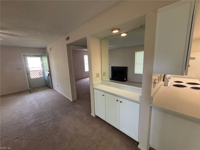 interior space featuring a textured ceiling, visible vents, a fireplace, baseboards, and carpet flooring