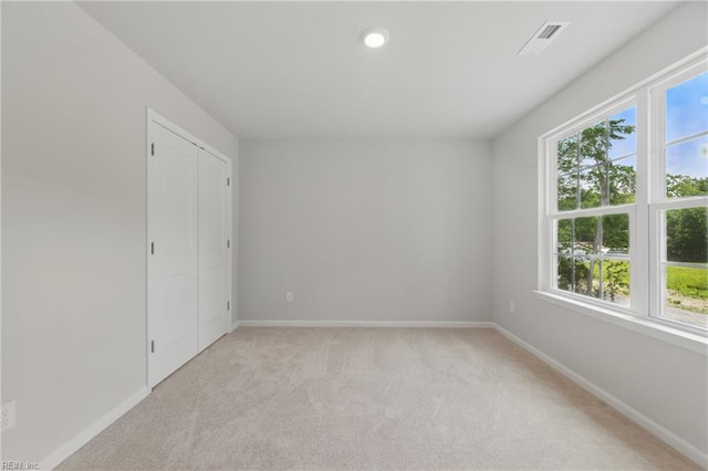 spare room featuring baseboards, light colored carpet, and a healthy amount of sunlight