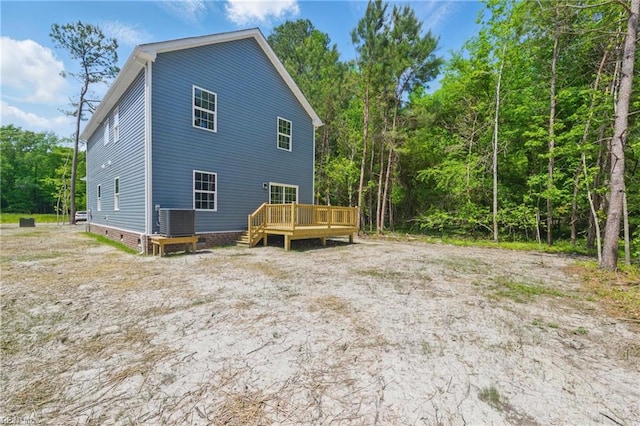 back of property featuring crawl space, central air condition unit, a deck, and a forest view