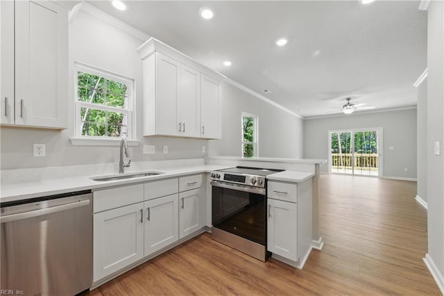 kitchen with crown molding, a sink, light countertops, a peninsula, and stainless steel appliances