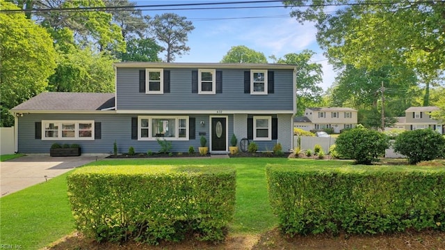 colonial house featuring fence and a front yard