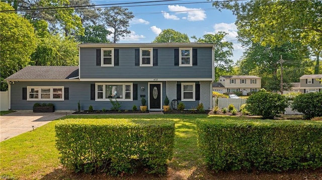 colonial house featuring fence and a front yard